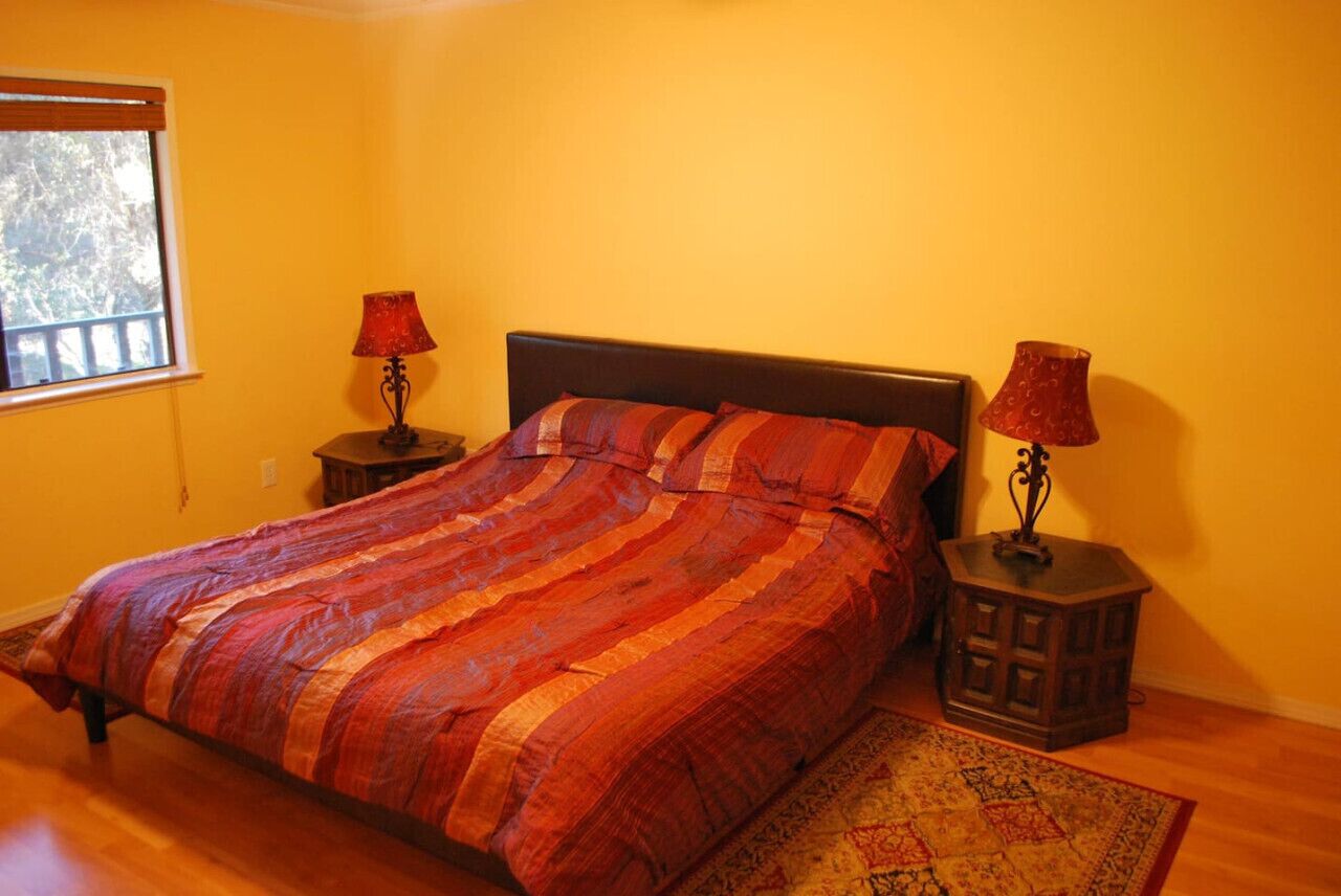 A bedroom with a bed, two nightstands, a window, and a rug.