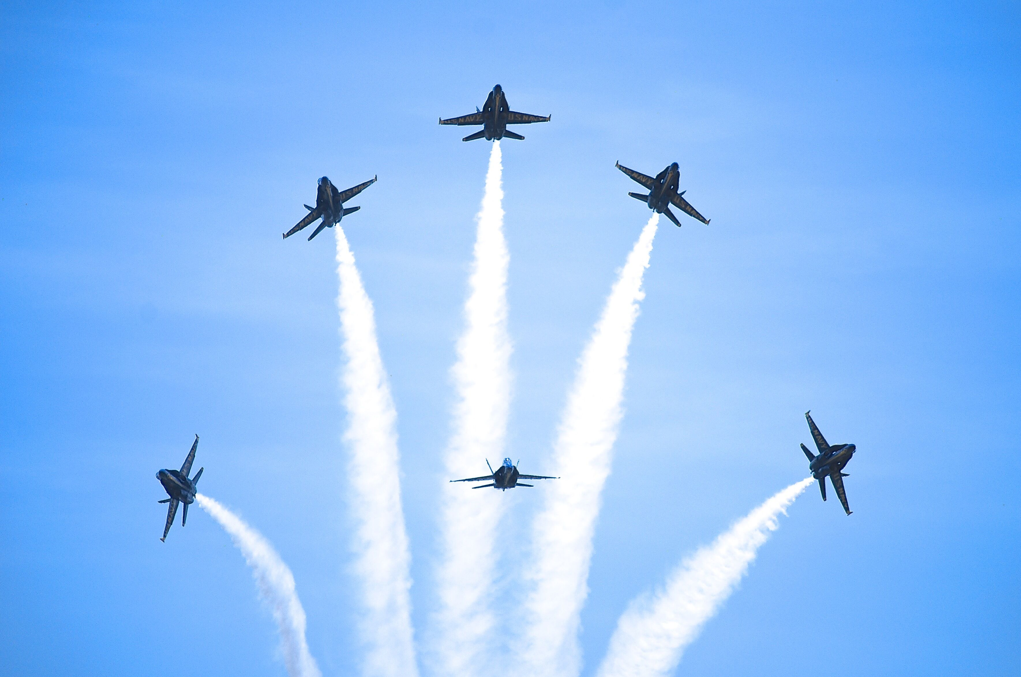 Un groupe de cinq avions de chasse volant en formation et laissant derrière eux des traînées de fumée.