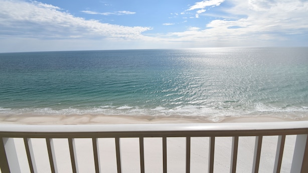 A balcony overlooking a beach with a view of the ocean and a clear sky. - Enjoy this Beachfront Condo with Amazing Views! (Gulf Shores)