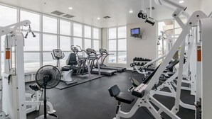 A gym with cardio machines, weightlifting equipment, and a fan. - Enjoy this Beachfront Condo with Amazing Views! (Gulf Shores)