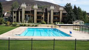 Relax by the pool surrounded by lush greenery and a scenic mountain backdrop.