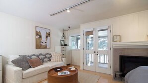 A modern living room with a white sofa, a round wooden coffee table, and a fireplace. - Cottonwood Studio  in Sun Valley (Sun Valley)