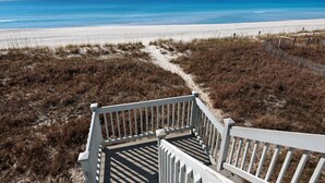A wooden staircase leading to a beach with a clear view of the ocean.