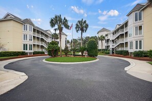 A residential complex with multiple-story buildings, a central landscaped area, and a curved driveway.