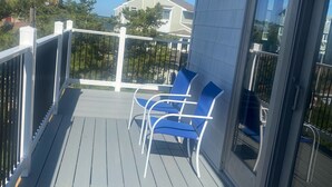 Eine Holzterrasse mit zwei blauen Stühlen und einer Glastür.