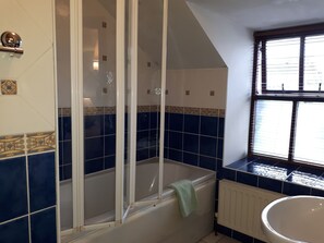 A bathroom with a bathtub, a shower, and a window. - Quaint with the Perfect Location Row House in Killarney Town Centre (Killarney)