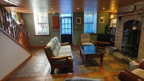 Un salon chaleureux avec une cheminée, des sièges confortables et un escalier menant à un autre niveau.