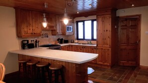 Une cuisine avec des meubles de rangement en bois, un grand îlot central doté de tabourets, un four à micro-ondes et un évier.
