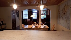 Un coin repas avec une table en marbre et des chaises en bois, deux lampes suspendues et une grande carte accrochée au mur.