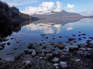 A calm lake with a mountain in the background and a rocky shoreline. - Quaint with the Perfect Location Row House in Killarney Town Centre (Killarney)