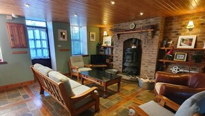 Un salon chaleureux, avec des meubles en bois, une cheminée et un sol carrelé en pierre.