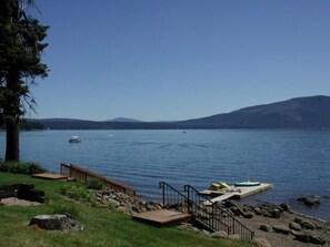 A lakeside view with a dock, boats, and a mountainous backdrop.
