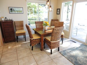 A dining area with wicker chairs, a wooden table, and a vase of sunflowers.