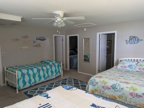 Quarto com duas camas, ventoinha no teto e detalhes decorativos com tema de peixes.