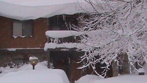 Ein schneebedecktes Gebäude mit einem Fenster und einem Baum im Hintergrund.