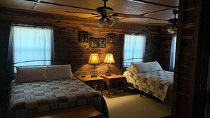 A room with two beds, a ceiling fan, wooden walls, and framed artwork. - Beautiful Log Cabin. Sleeps 2-8. Reds Landing boat ramp .5 mi away. A+ fishing. (Norfork)