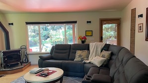 A living room with a dark brown sofa, a round coffee table, and a fireplace. - Cozy House near the Hawaii Volcanoes National Park & Volcano Village on 1.5 Acre (Volcano)