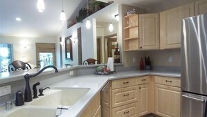 A modern kitchen with a large sink, wooden cabinets, and a stainless steel refrigerator. - Cozy House near the Hawaii Volcanoes National Park & Volcano Village on 1.5 Acre (Volcano)