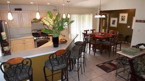 A kitchen with a central island, bar stools, a dining table with chairs, pendant lights, and a potted plant. - Cozy House near the Hawaii Volcanoes National Park & Volcano Village on 1.5 Acre (Volcano)