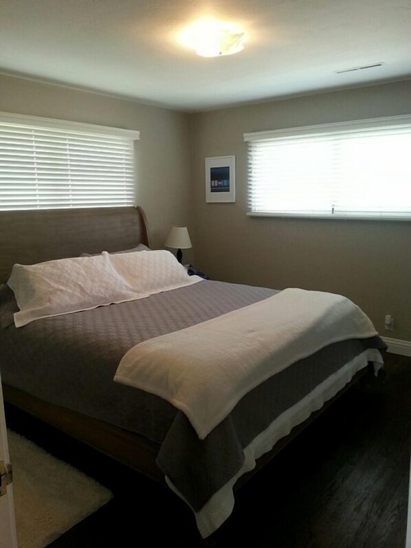 A neatly made bed with a headboard, two bedside tables, and a window with blinds. - On the water in Pacific Grove (Pacific Grove)