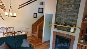 A cozy living room with a fireplace, wooden furniture, and a staircase leading to another level. - White Mountain Four Season Vacation Getaway!! (Lincoln)