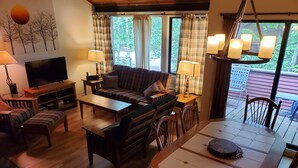 A cozy living room with a sofa, TV, and dining area with a table and chairs. - White Mountain Four Season Vacation Getaway!! (Lincoln)