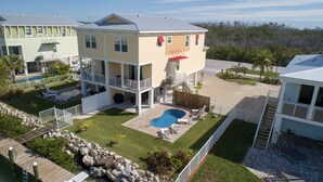 Un edificio de varios pisos con piscina, mobiliario de exterior y una terraza vallada.