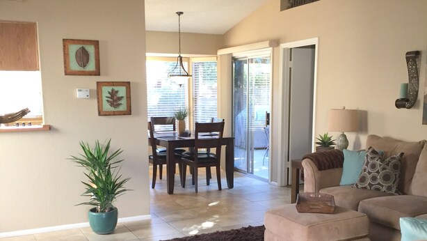 A spacious living room with a ceiling fan, a dining area with a table and chairs, a large window, and a sliding glass door leading to a patio. - Well Maintained, Super Clean, and Perfect Location (Peoria)