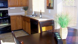 A kitchen with wooden cabinets, a microwave, an oven, a dishwasher, a sink, and a dining table with chairs. - Well Maintained, Super Clean, and Perfect Location (Peoria)