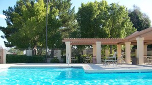 A swimming pool with clear blue water, surrounded by a covered patio area with chairs and tables. - Well Maintained, Super Clean, and Perfect Location (Peoria)