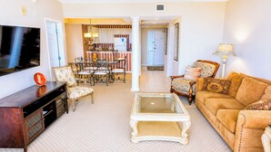A living room with a TV, a coffee table, a sofa, and a dining area with chairs.