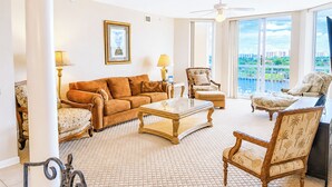 A spacious living room with a large window, a ceiling fan, and a view of a cityscape.
