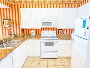 A kitchen with white cabinets, a microwave, a stove, and a refrigerator.