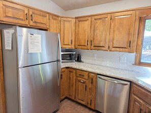 A kitchen with wooden cabinets, a stainless steel refrigerator, a microwave, and a dishwasher.