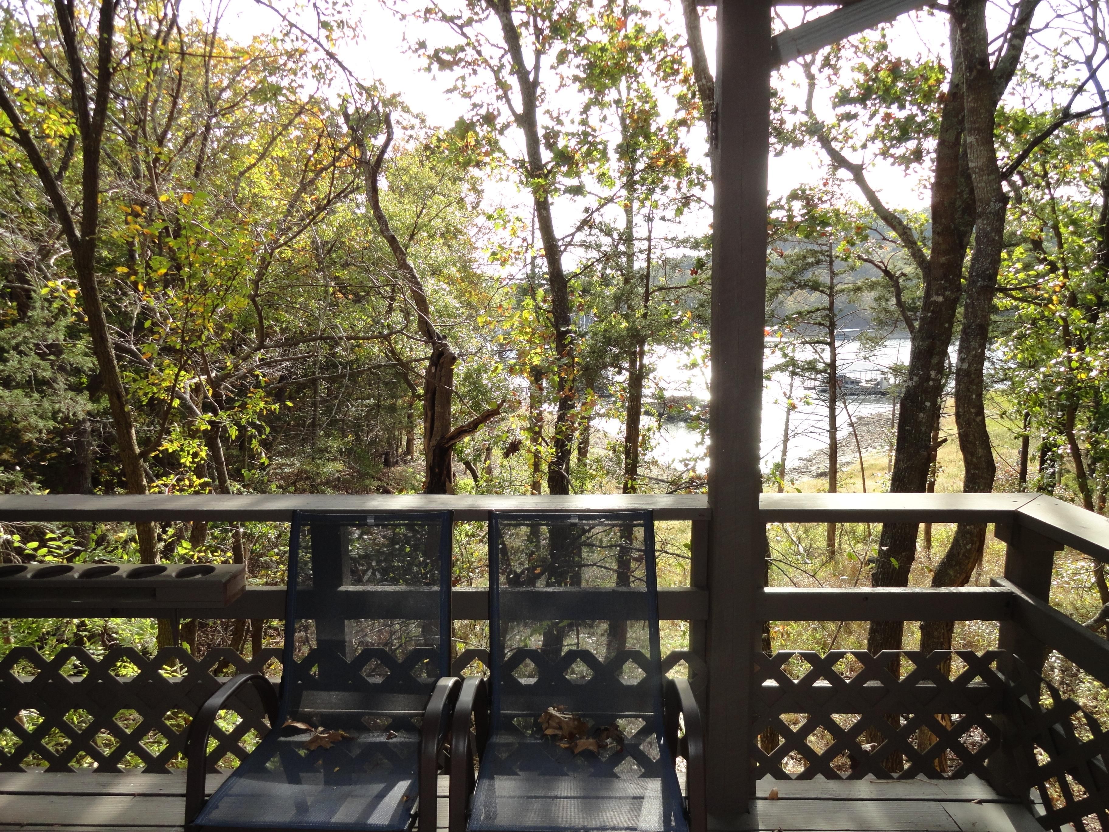 A wooden deck with benches overlooking a forested area and a body of water.