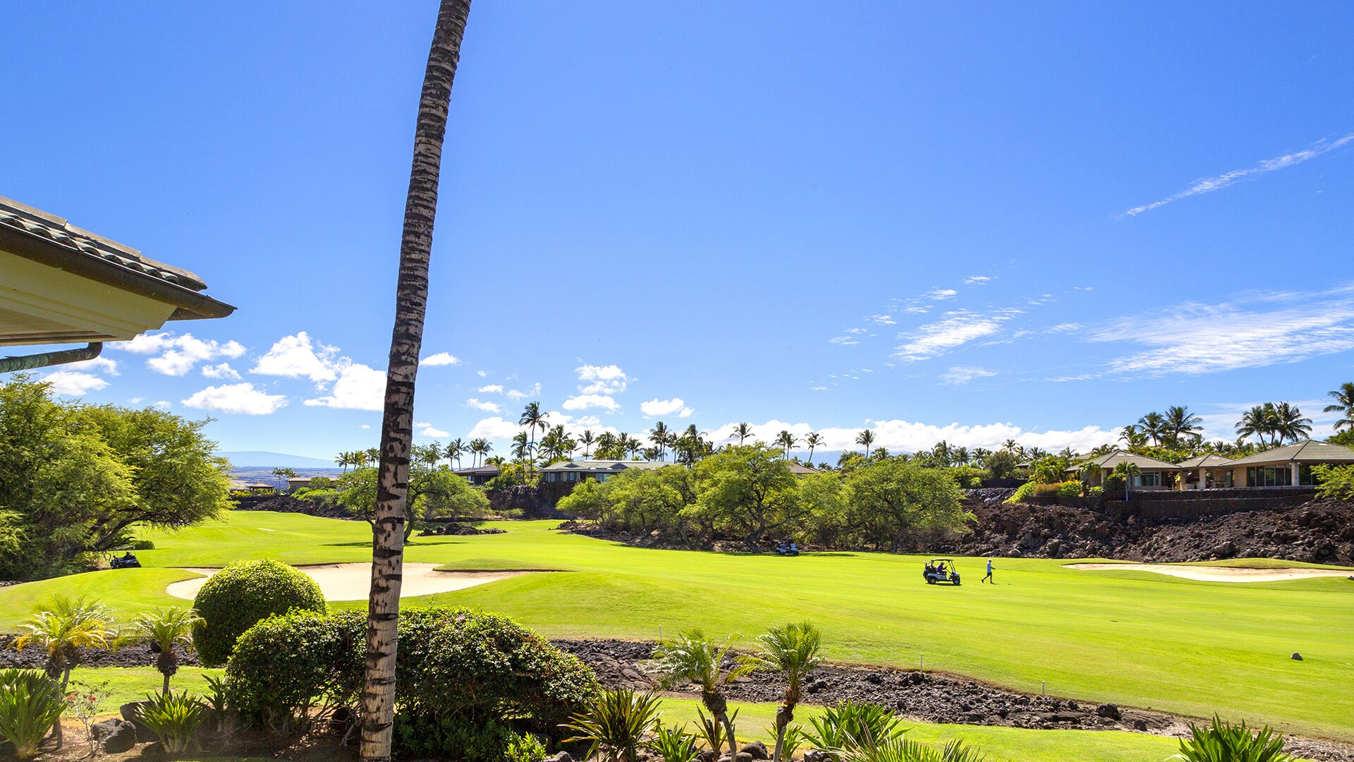 A golf course with a clear view of the green, sand bunkers, and surrounding trees.