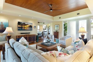 A spacious living room with a ceiling fan, a television, and a dining area with chairs and a table.