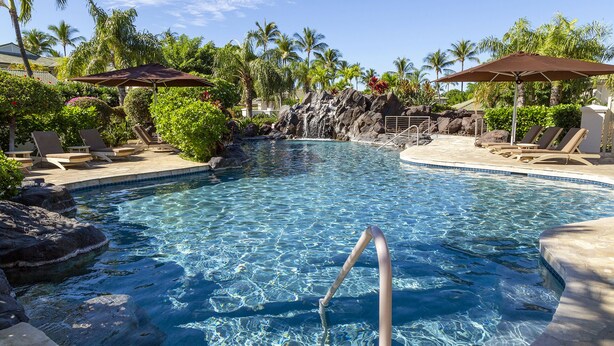 A clear pool with a rock waterfall, surrounded by lounge chairs and umbrellas. - The Islands at Mauna Lani - Hikialani Residences B2 - Walk to beach and shops (Kamuela)