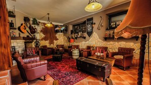 A cozy lounge area with leather sofas, a patterned rug, and a stone wall backdrop. - Deluxe suite in the middle of Plitvice lakes (Plitvice lakes)