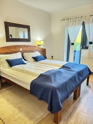 A neatly made bed with a headboard, a bedside lamp, and a window with curtains.