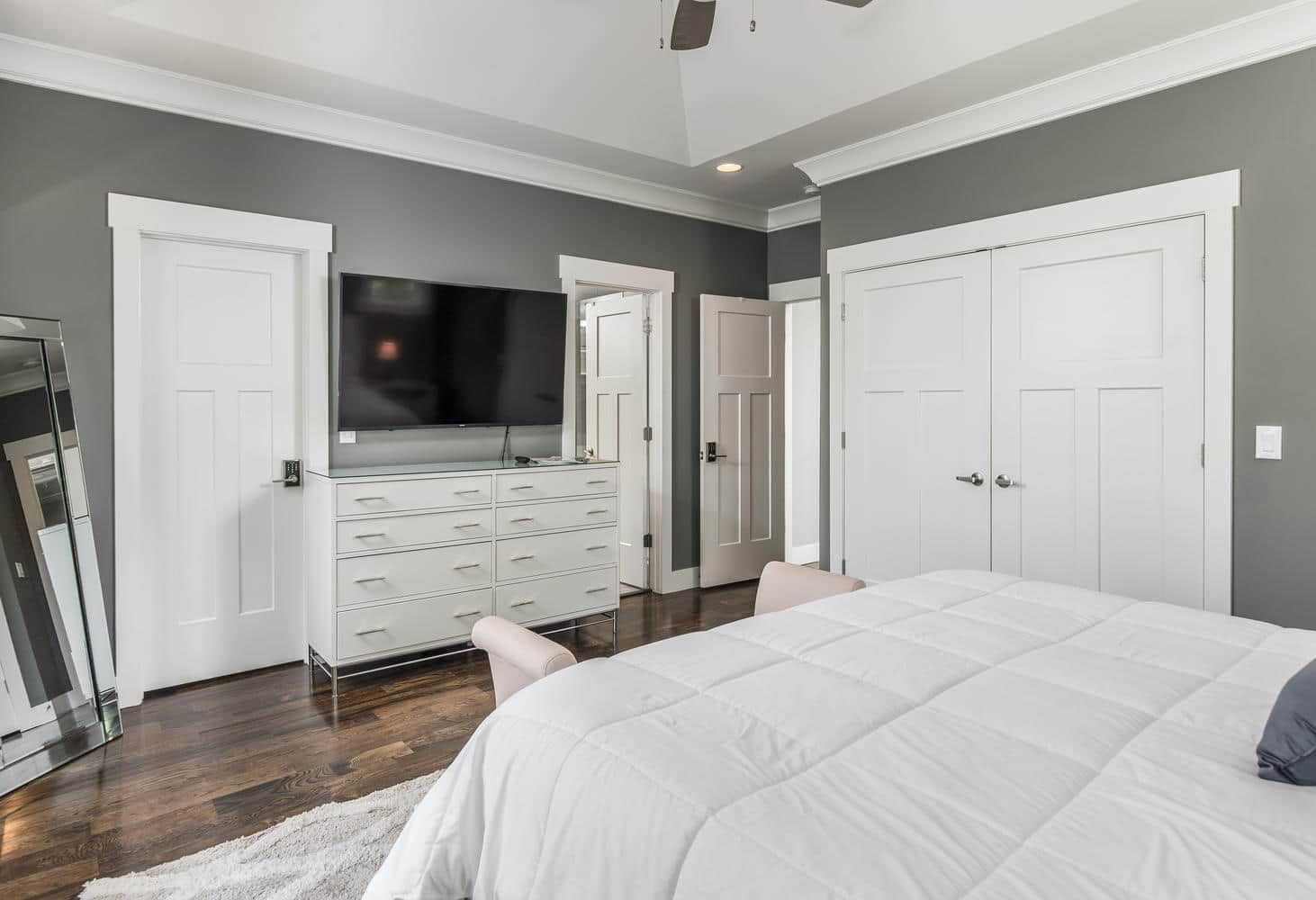 Un dormitorio con una cama grande, un aparador, un televisor y dos puertas.