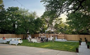 An outdoor event with tables and chairs arranged in a grassy area, surrounded by a wooden fence and trees. - Downtown Mansion 8BD/6BA w/ 2 HOTTUBS - Sleeps 24+ (Nashville)