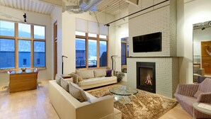 Ein modernes Wohnzimmer mit Kamin, großen Fenstern und einer gemütlichen Sitzecke.