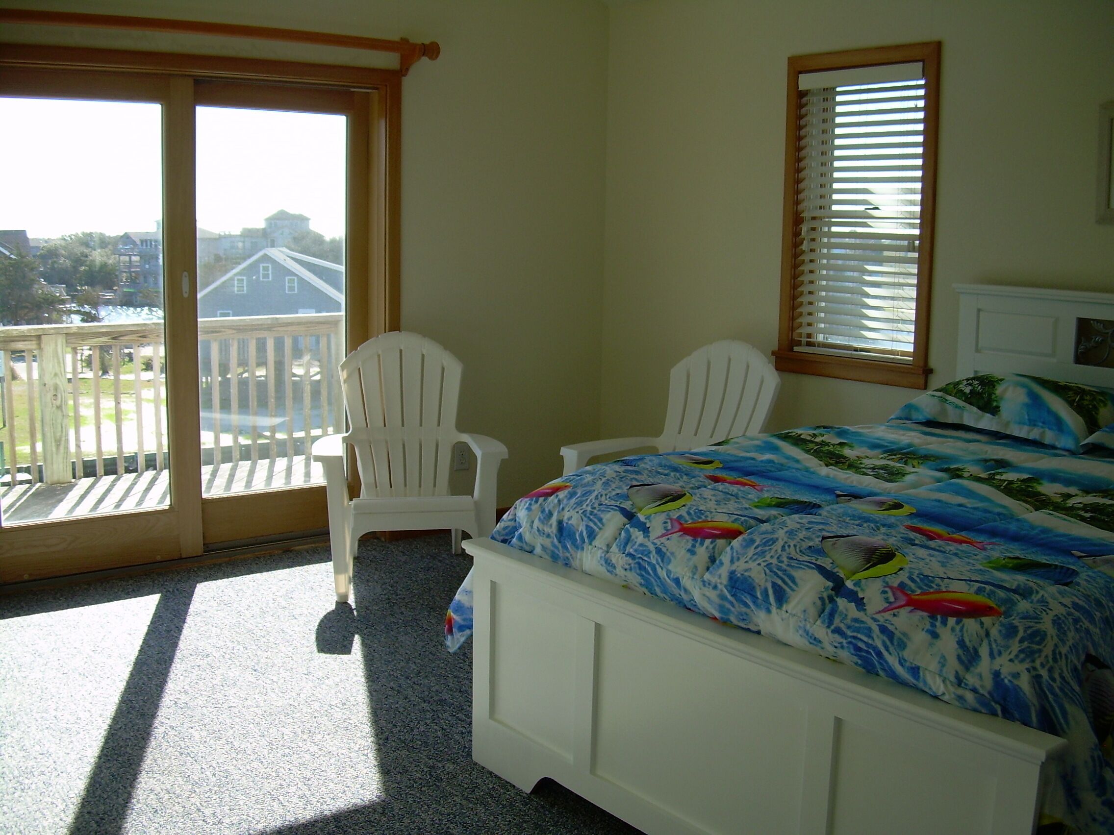 Une chambre à coucher avec un lit, deux chaises, une fenêtre et un balcon.
