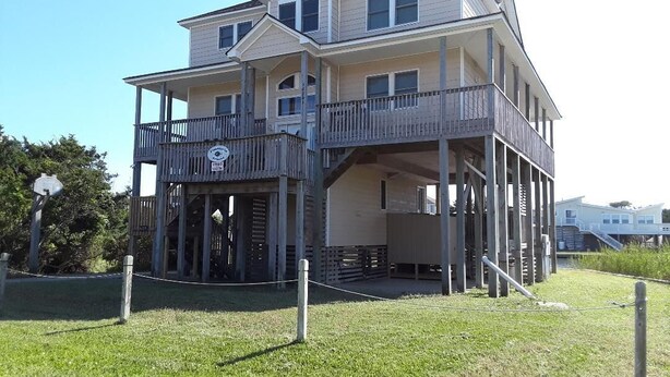 A two-story house with a balcony on the first floor and a covered porch on the second floor.