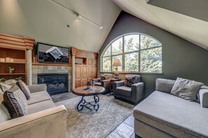 A spacious living room with a fireplace, comfortable seating, and a large window providing natural light.