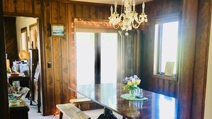 A dining area with a long table, benches, and a chandelier.