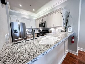 A modern kitchen with granite countertops, stainless steel appliances, and white cabinetry. - Modern Portland Condo,  Near Zupan’s, OHSU, River Trails, Dining & Skyline Views (Portland)