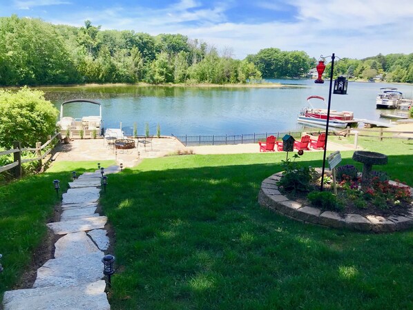 A lakeside patio with outdoor seating, a stone pathway, and a boat dock. - Authentic Log Cabin on Beautiful Silver Lake in Traverse City MI. Pet Friendly! (Traverse City)