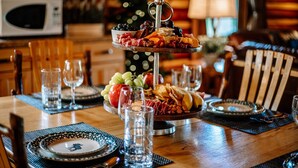 Een drijvlak plank met charcuterie met diverse vleessoorten, kazen en fruit op een houten tafel.